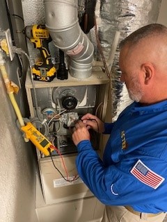 An AC TEX technitian reading a multimeter to troubleshoot furnace repairs