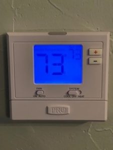 A thermostat showing the temperature of 73 degrees.