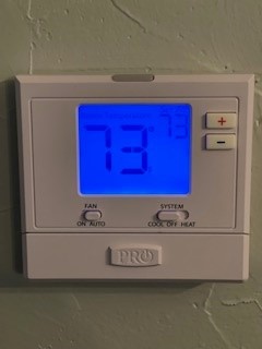 A thermostat showing the temperature of 73 degrees.